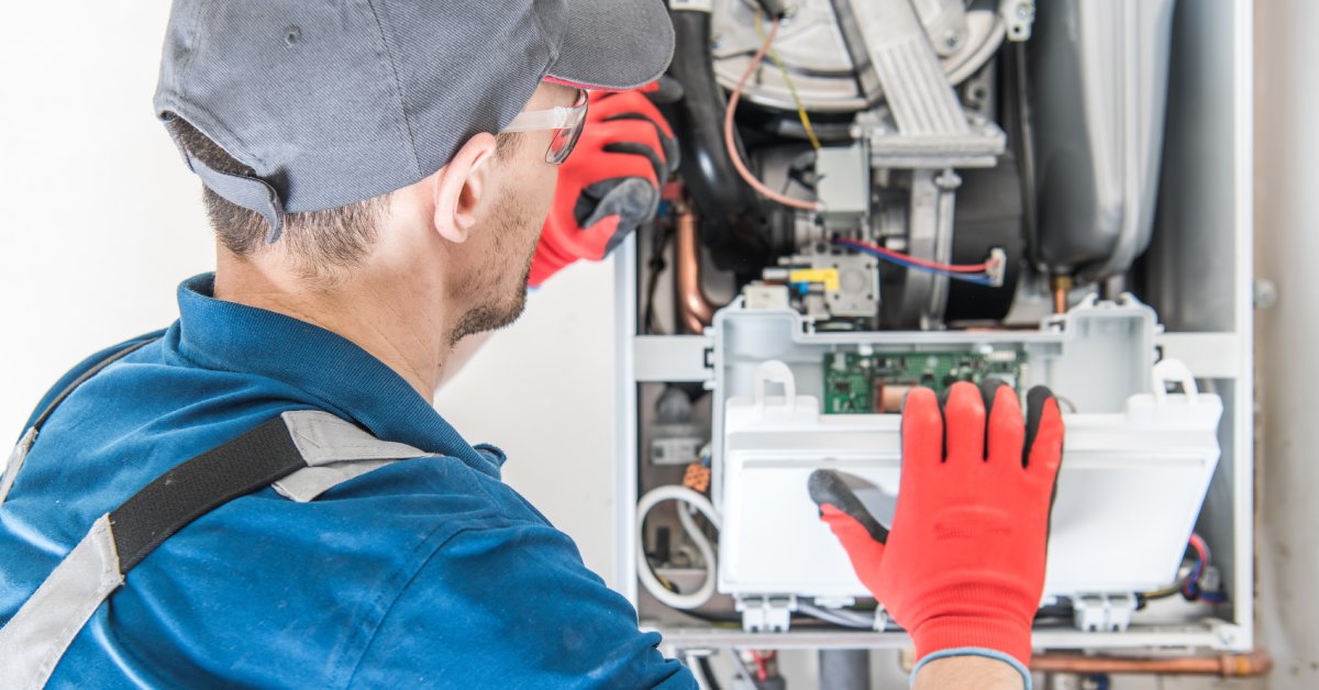 An over-the-shoulder shot of a maintenance personnel working on the internal components of a furnace.